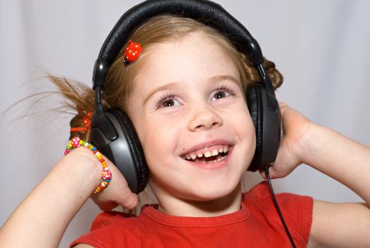smiling little girl listening to music with headphones
