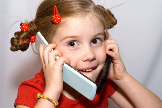 little girl talking on two mobile phones and looks at camera