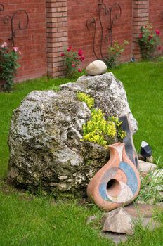 nice backyard decoration, stone with yellow flowers, ceramics on the grass