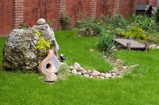 nice backyard decoration, stone with yellow flowers, ceramics on the grass etc