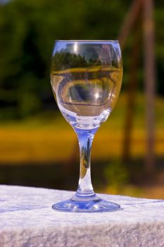 Empty wine glass on table on colourfull background. Outdoors, summer.