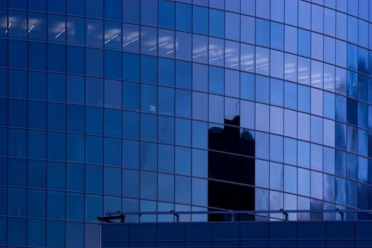 Blue corporate office building facade and reflection of other skyscraper in late evening