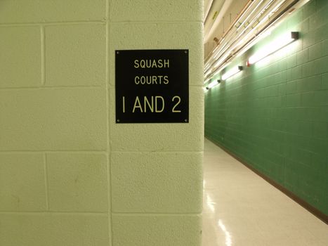 Squash court plaque on a wall in a long hallway