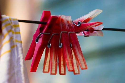 Red plastic clothespins and towel on a black washing line. Selected focus on clothespins with soft and diffused background.