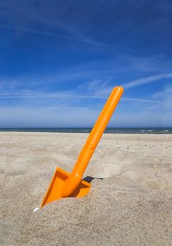 Orange plastic spade in the sandy seashore