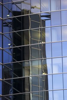Corporate office building facade and reflection of other skyscraper in windows