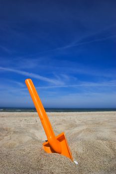 Orange plastic spade in the sandy seashore