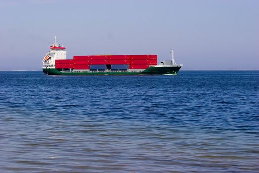 Cargo ship with red containers in sea. Place for copy text.