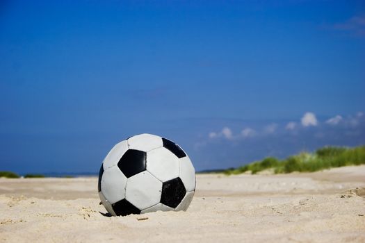 Soccer ball on sandy beach after game