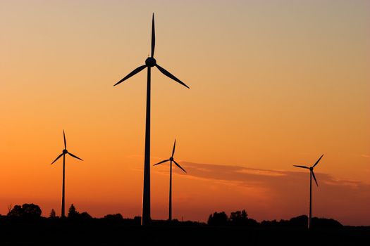 Four windturbines against dramatic sunset producing environment friendly energy