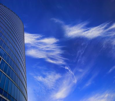 Office skyscraper facade on deep blue sky with white clouds. Place for copy space.