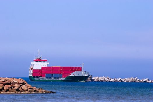 Cargo ship with red containers entering port