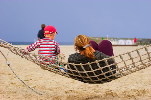 Mother and child in hammock resting at sandy beach