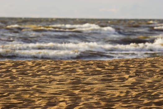 Many footprints in the sandy beach and sea in a background.