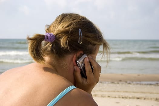 Young woman talking by cell phone at the beach.