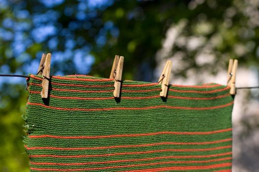 Red and green striped towel pegged to a clothesline with four clothespins. Place for copy text