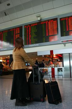 Young woman looking for flight in airport timetable