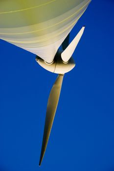 Wind power generator turbine against clear blue sky