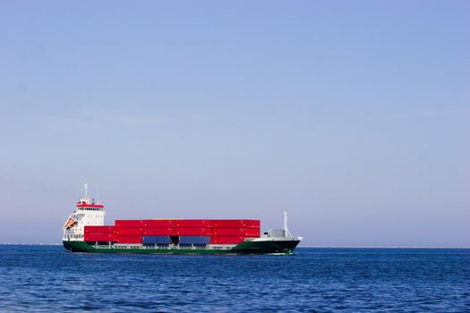 Cargo ship with red containers in open sea