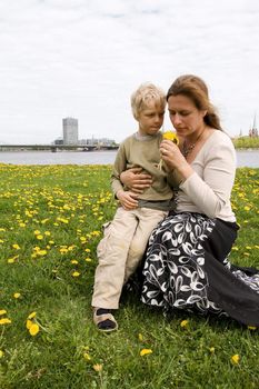 Mother and son in Dandelion meadow. Riga city in background