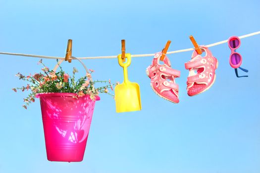 Summer toys and sandals on clothesline against a blue sky