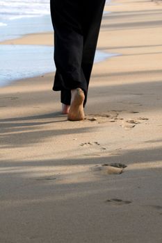 Woman walking on the beach, focus on foot