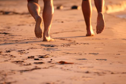 two men running on the beach by sunset