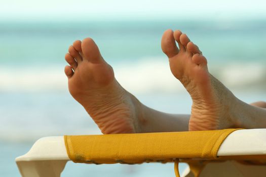 Close-up of the female feet resting on the beach 