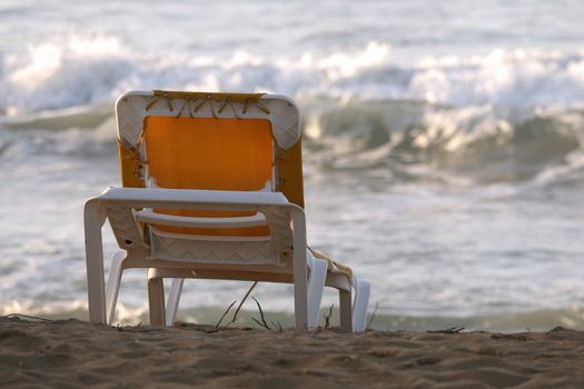 yellow chaise longue on the sand beach in the sunlight