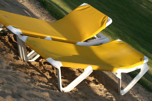 yellow chaise longues on the sand beach in the sunlight