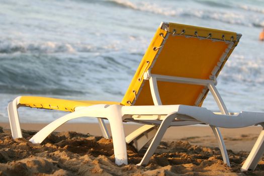 yellow chaise longue on the sand beach in the sunlight