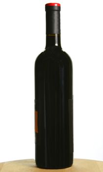 Single bottle of dark red wine on oak table, isolated