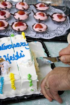 Cutting some anniversary cake with mousse cups in the background.