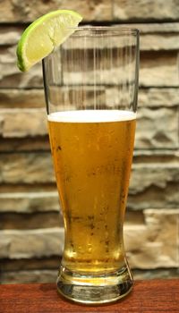 Refreshing beer with lime, against slate brick background