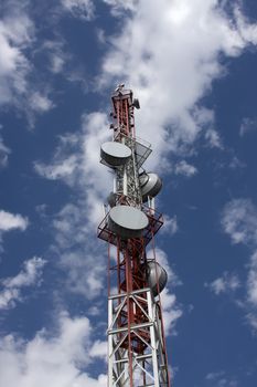 Celluar aerial in the blue sky with round transmitter