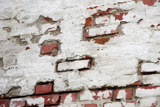 Fragment of old brick wall with white stucco