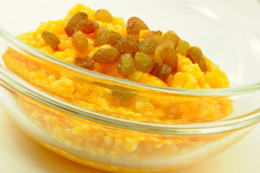 Pumpkin and Millet Gruel with Raisins in Transparent Bowl on White, Close-Up