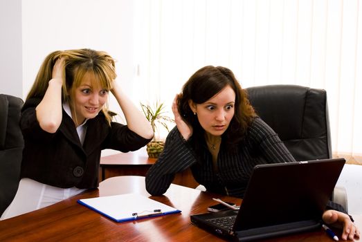 two surprised young businesswomen looking at the computer