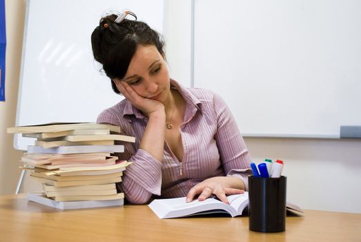 young student holding her head over books