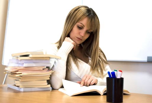 young student holding her head over books