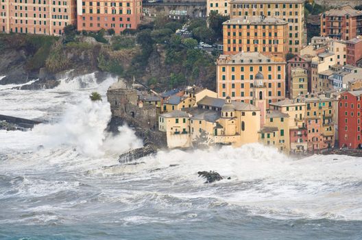 Waves break over the church and the castle in Camogli, Italy