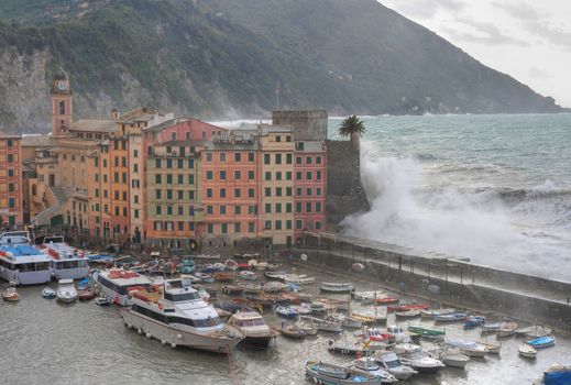 Waves break over the castle and the pier of Camogli harbor, Italy during a violent sea storm