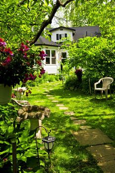 Path of steeping stones leading to a house in lush green garden