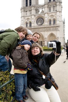 Group of tourists, members of one family taking self portrait at the famous Cathedrale Notre-Dame de Paris