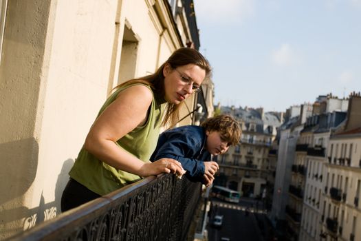 Mother and her son on balcony looking at city life.