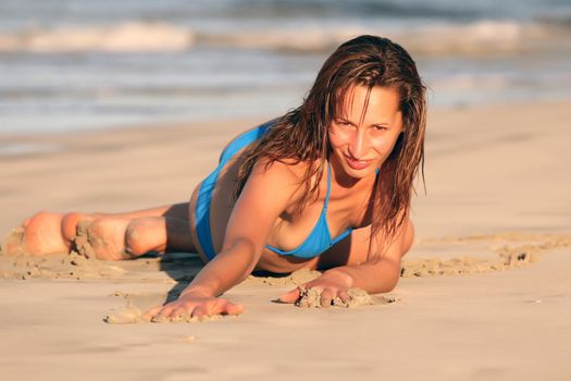 Jung woman posing on the beach by sunset