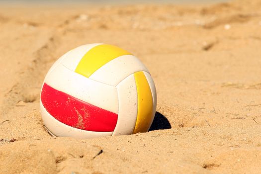 Beachvolleyball lying in sand
