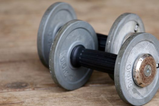 two dumbbells lying on the wooden ground