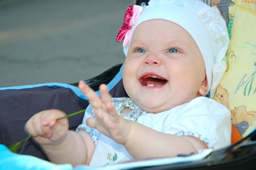 Pretty little girl with blue eyes  (baby) laughing in carriage.
