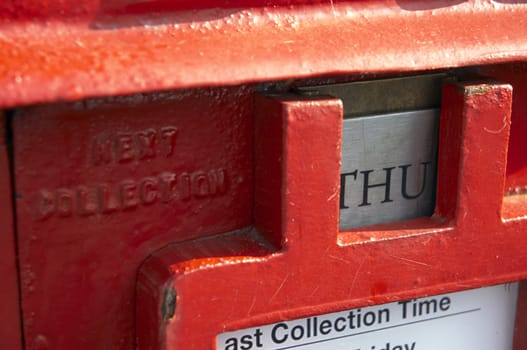 A red English post box showing the next collection time